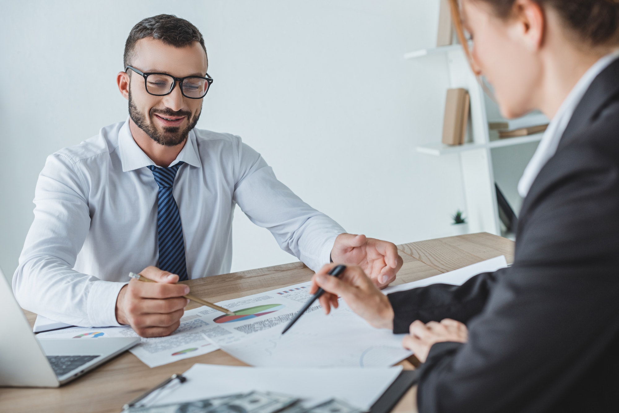 cheerful financiers pointing on documents in office