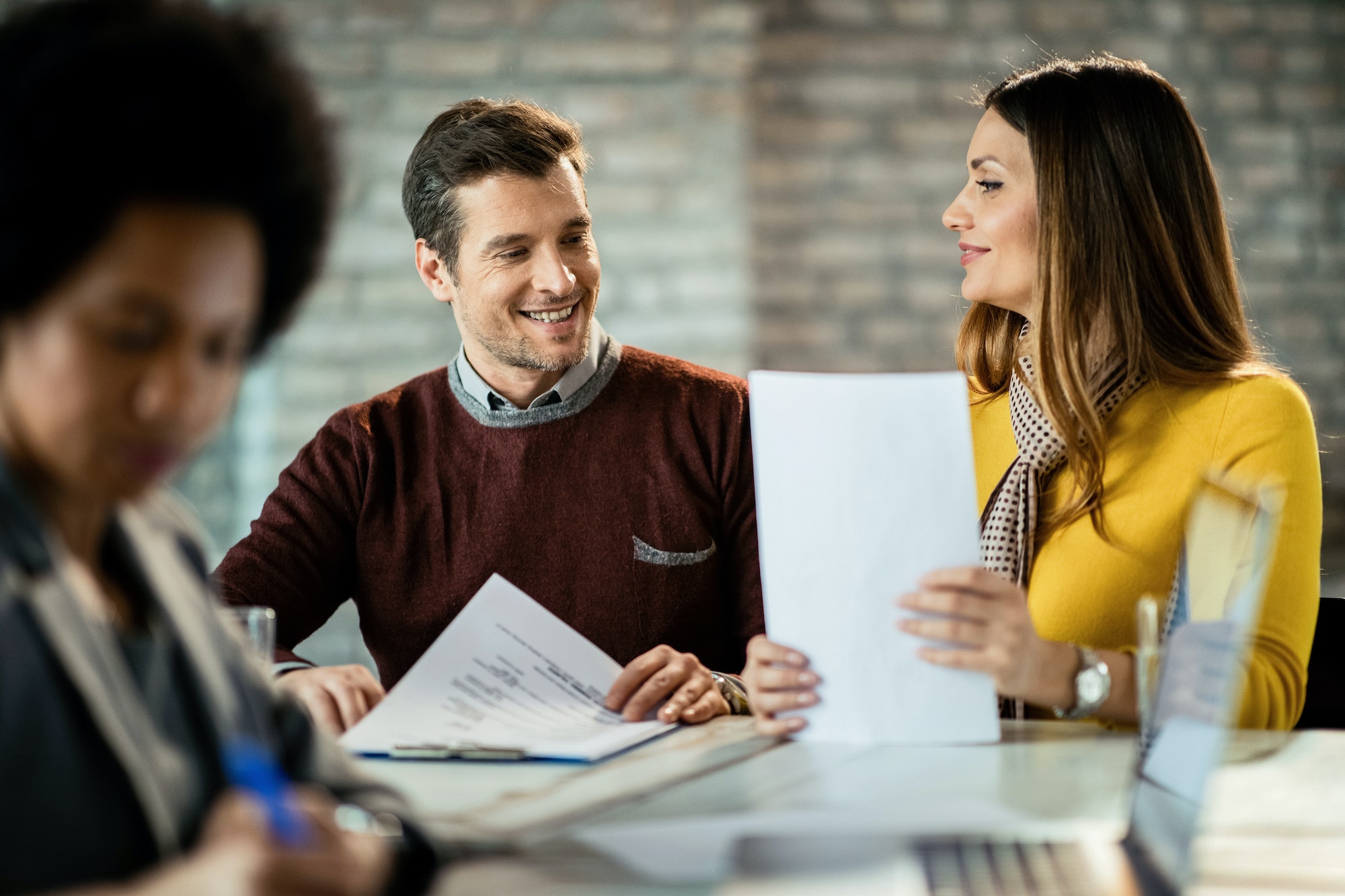 happy couple consulting each other while being on a meeting with financial advisor