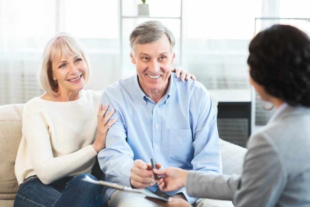 happy mature couple talking to financial advisor at home